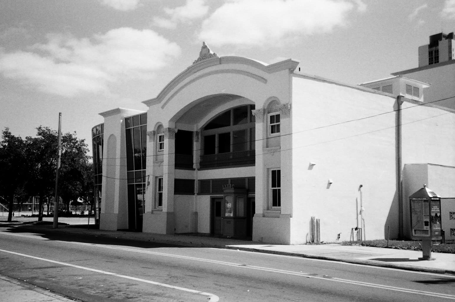 A black-and-white photograph of the Lyric Theater, a white building with a tall arched entrance