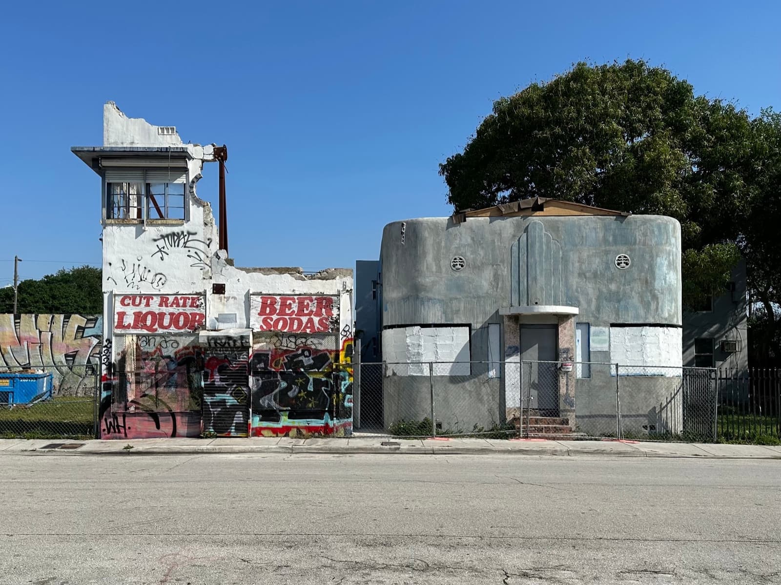 Two weathered low buildings in Overtown, one painted with old liquor-store lettering and graffiti