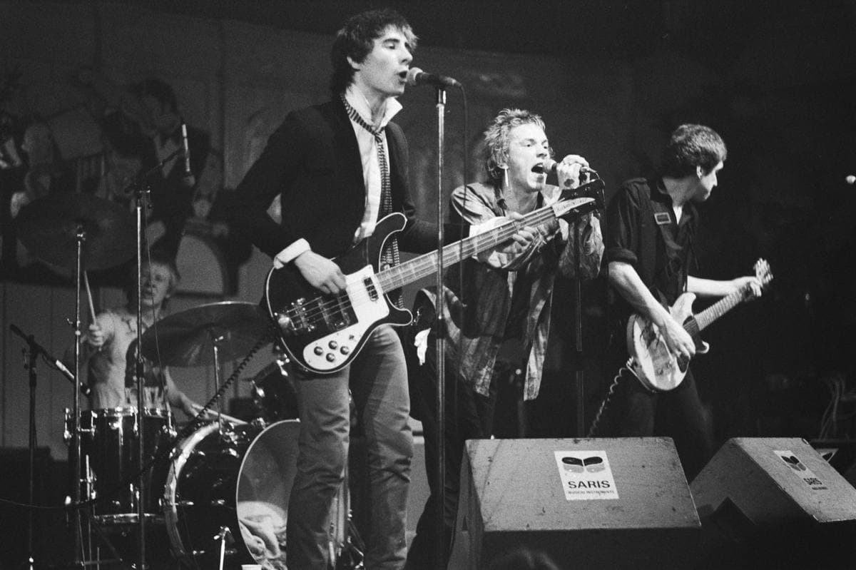 The four Sex Pistols on a small stage, drummer behind, three in a row at the front