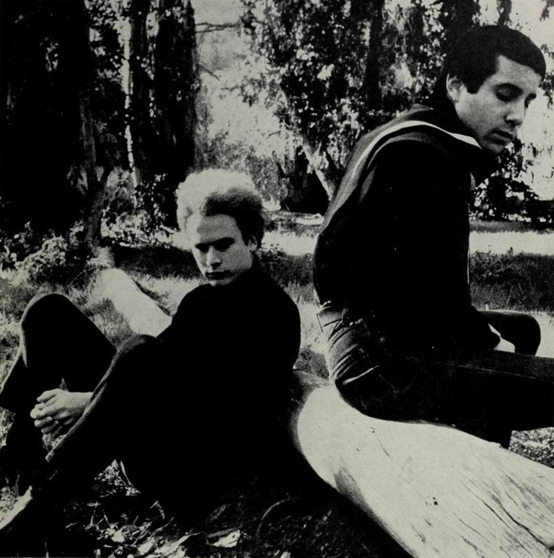 The two sitting on a felled log in long grass, Garfunkel barefoot