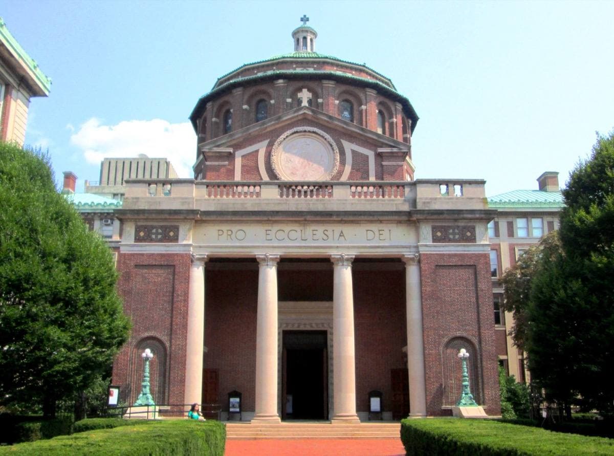 A red-brick domed chapel with a columned portico between hedges