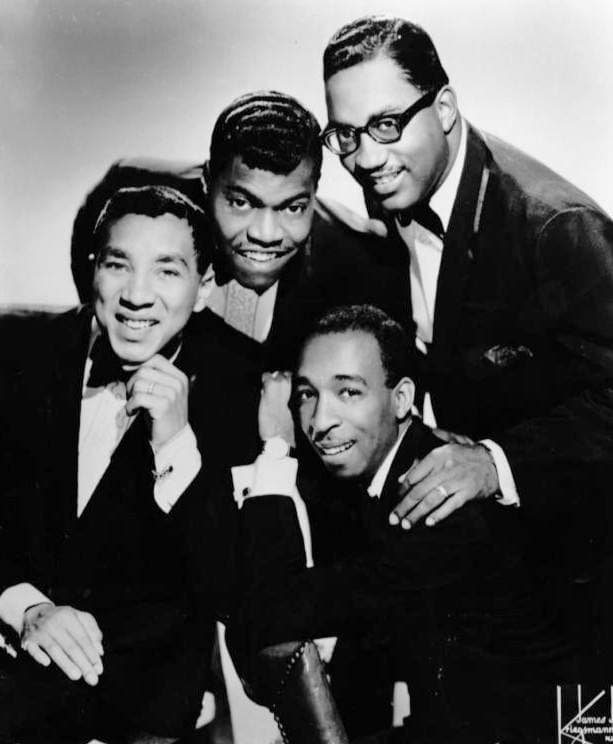Four men in slim suits stepping forward in a line, each on one foot