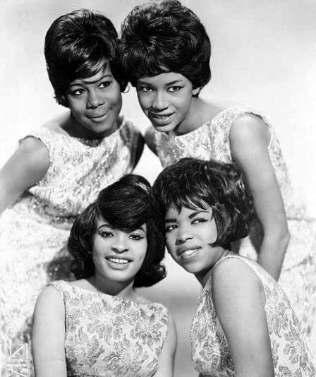 Four young women in matching sleeveless dresses posed close together