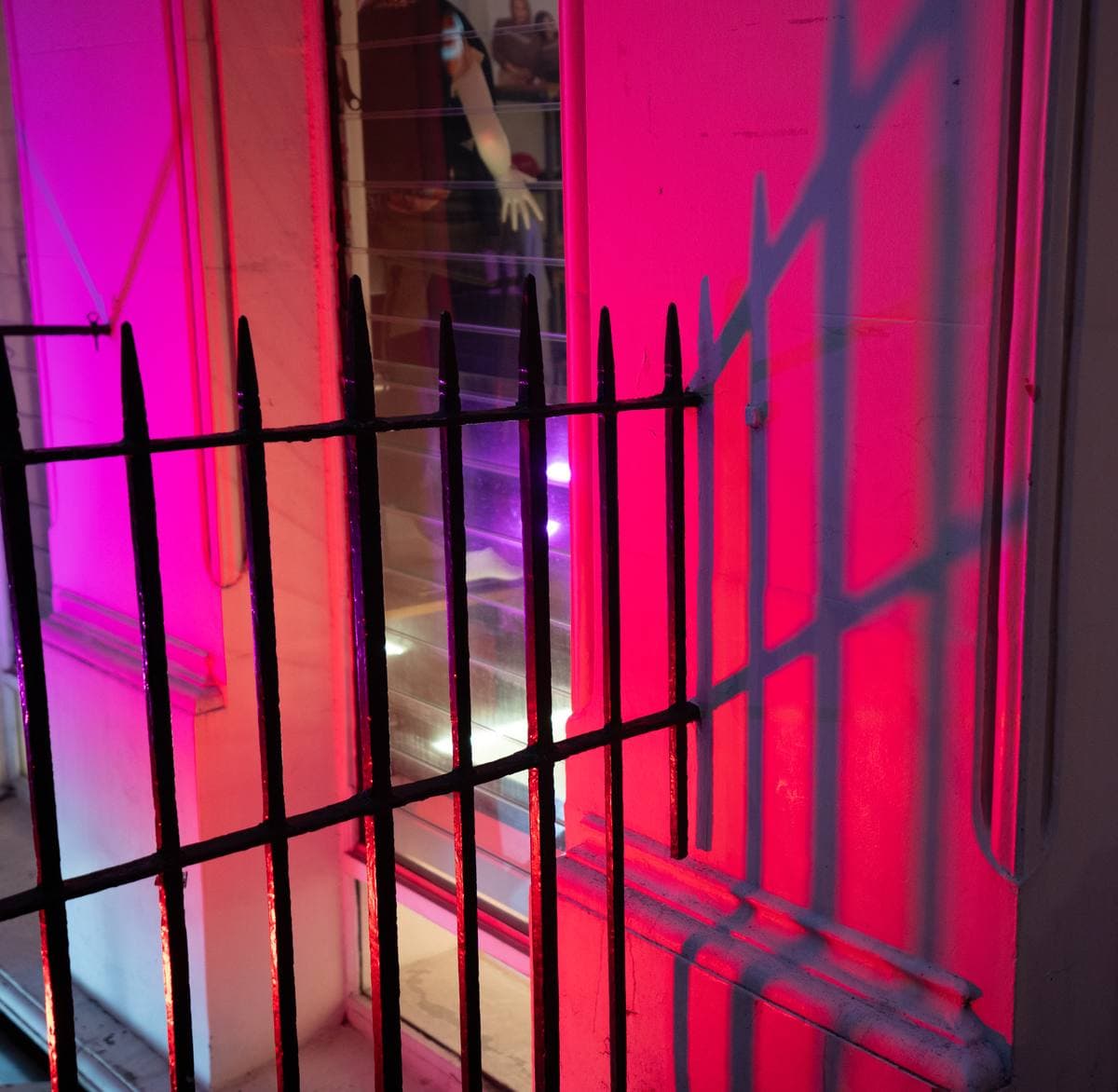 Black railings in front of a window lit pink and red
