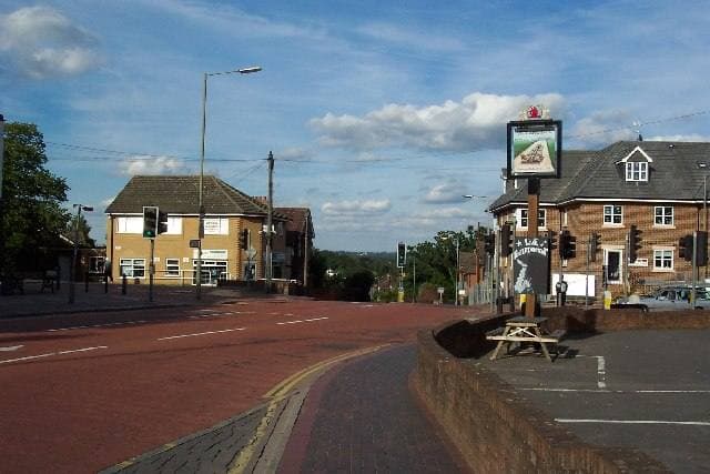 A village road junction with a pub sign and brick buildings