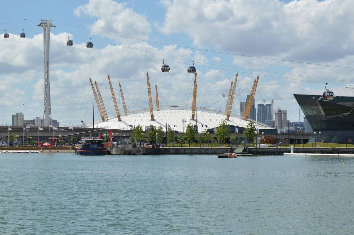 A white tented dome with yellow masts across the water
