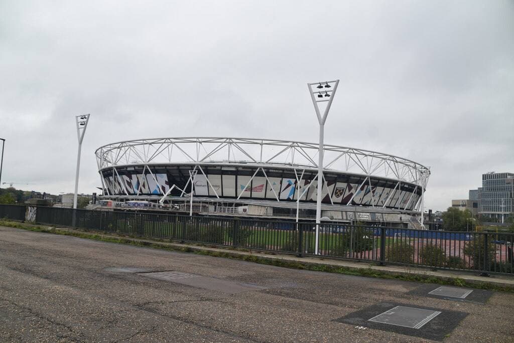A round stadium with a steel roof ring seen from a road