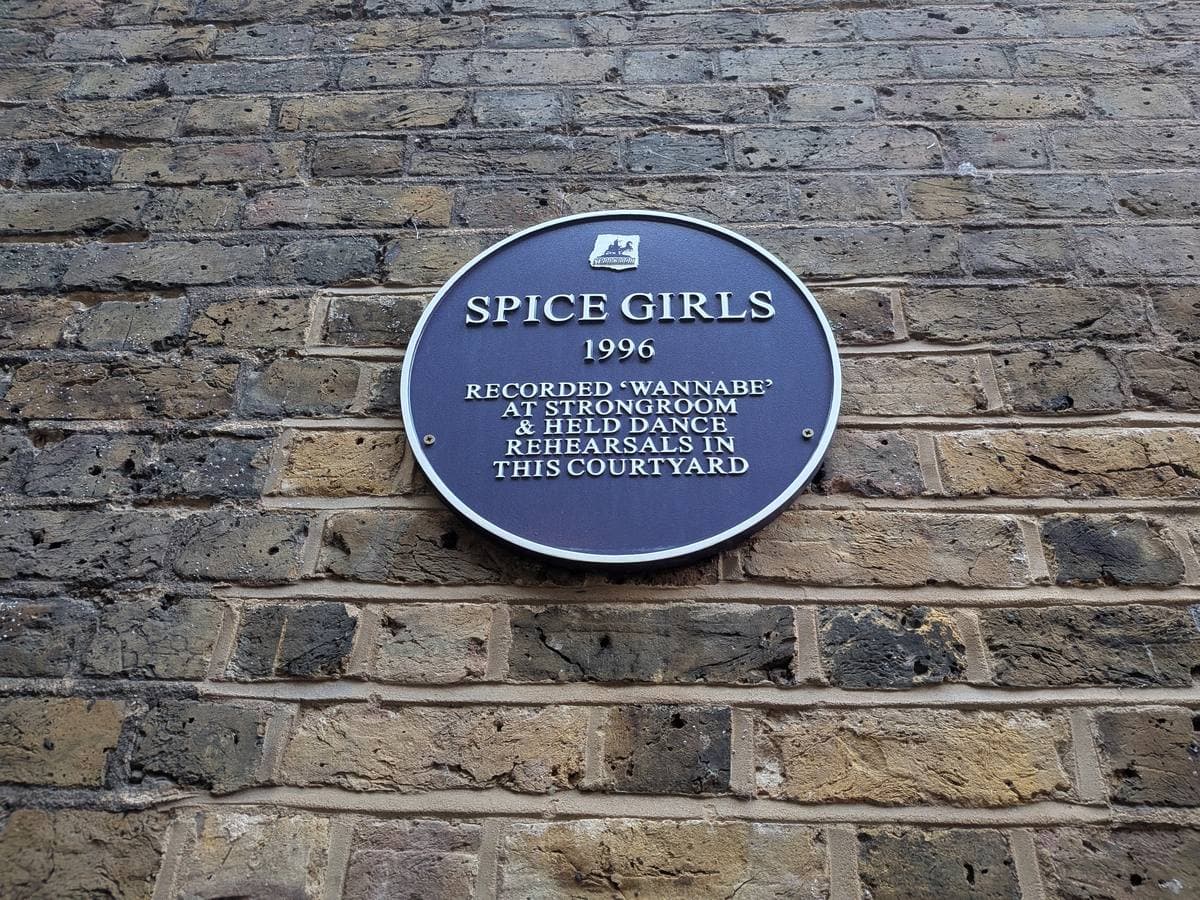 A round blue plaque on a London brick wall