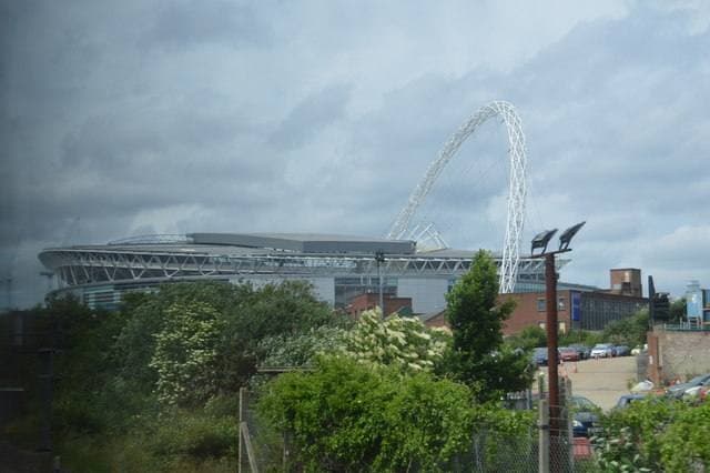 A white arch over a stadium roof under a grey sky