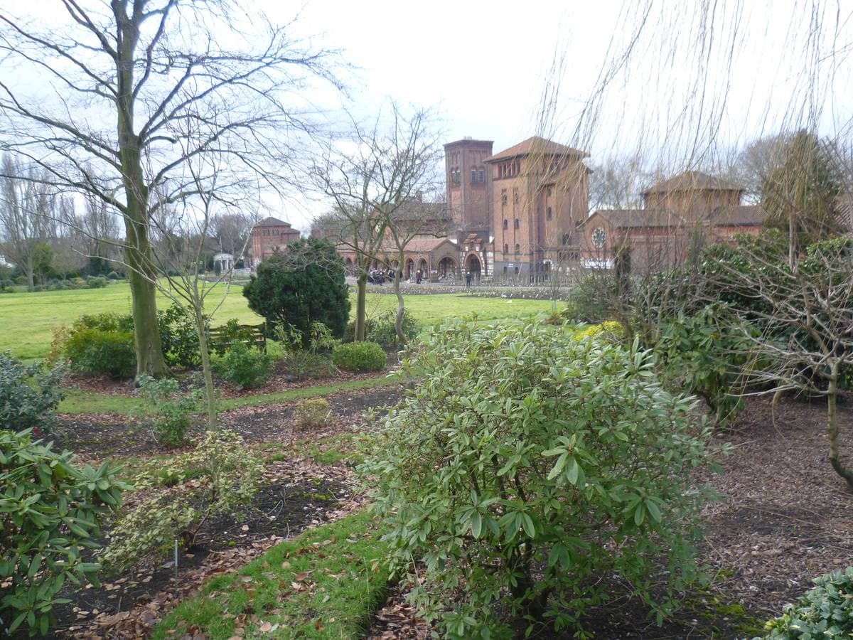 Lawns and shrubs before a red-brick building with towers