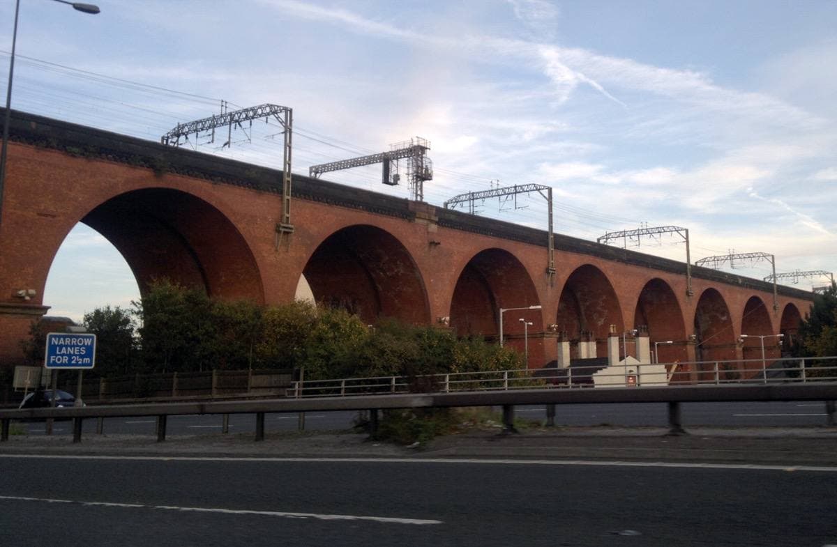 A long red-brick railway viaduct of many arches over a road