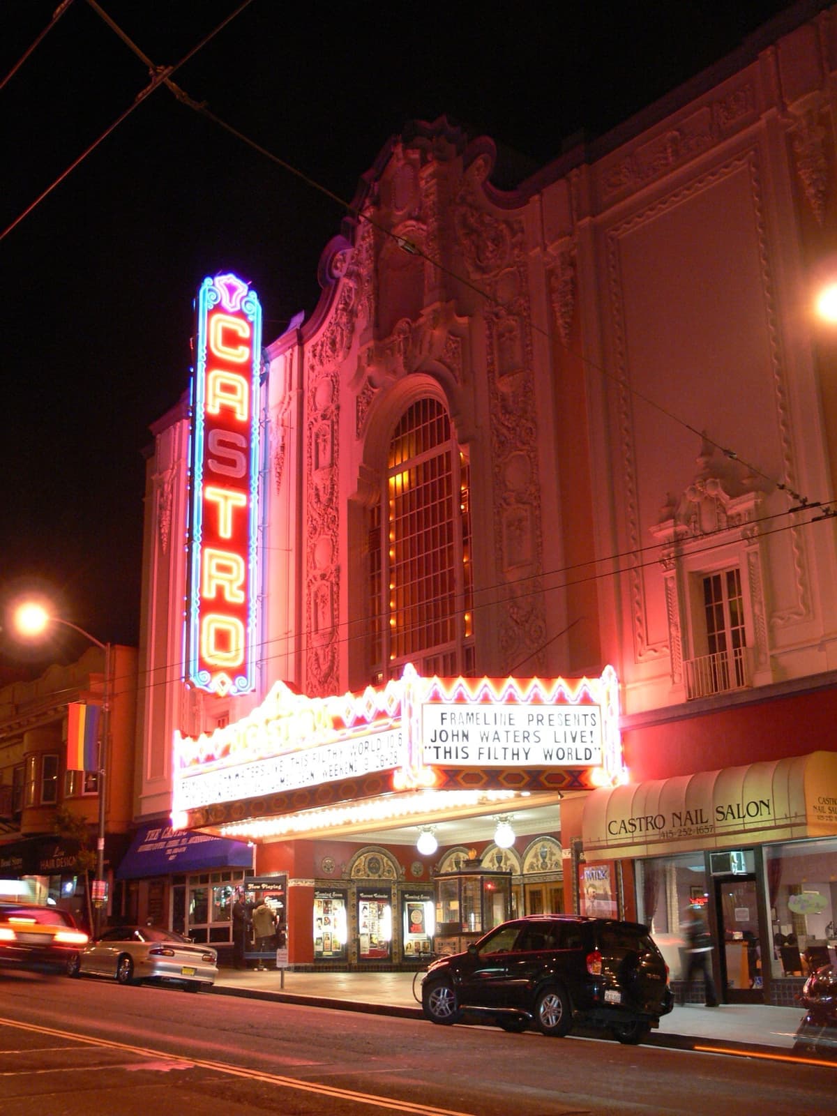 A red neon vertical sign spelling Castro above a lit marquee at night