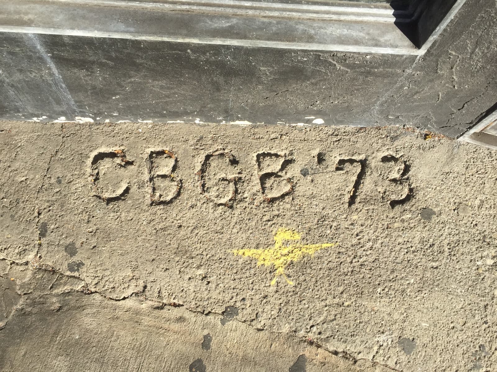 Close-up of letters and a date scratched into grey concrete