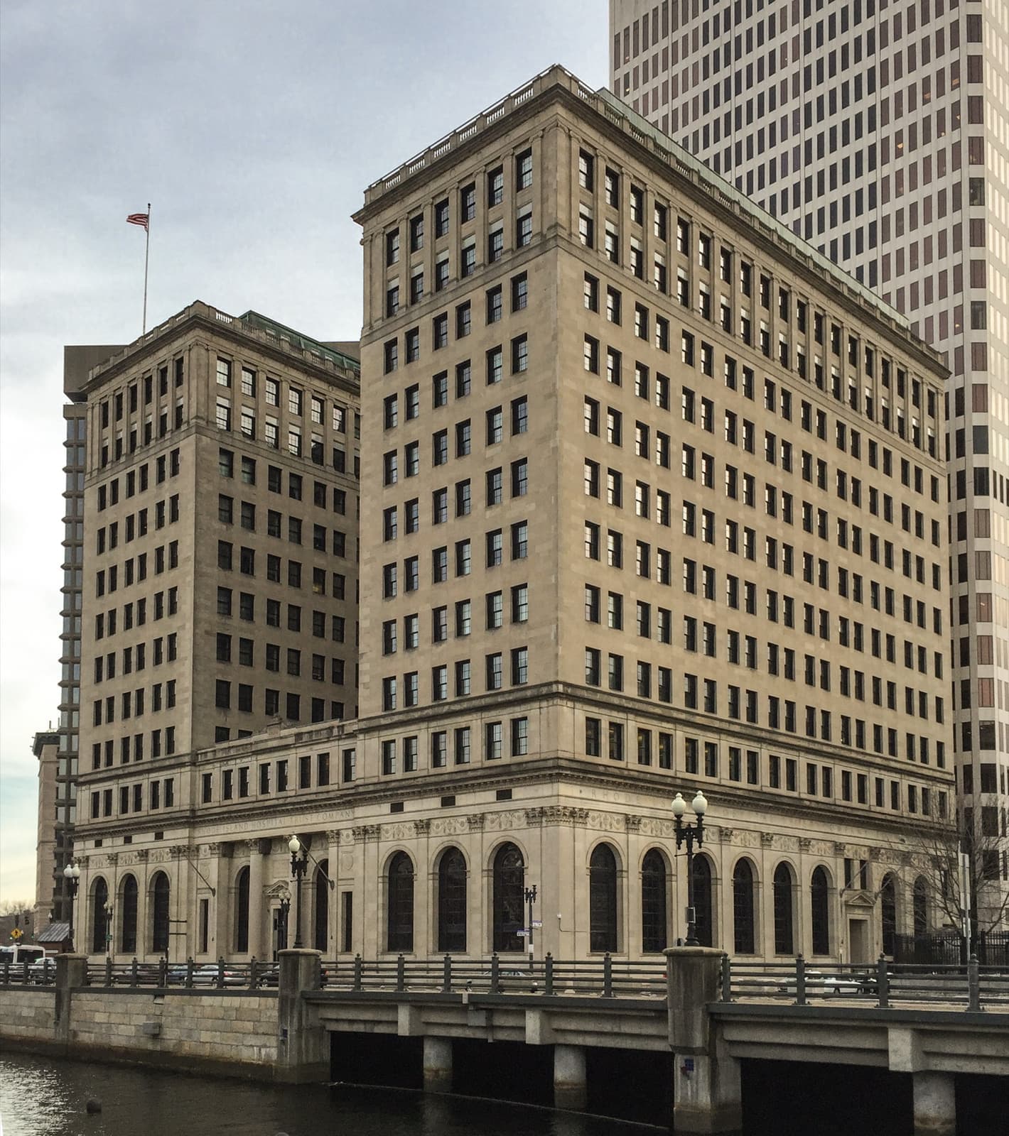 A tall pale stone office building with an arcade of arched windows at street level