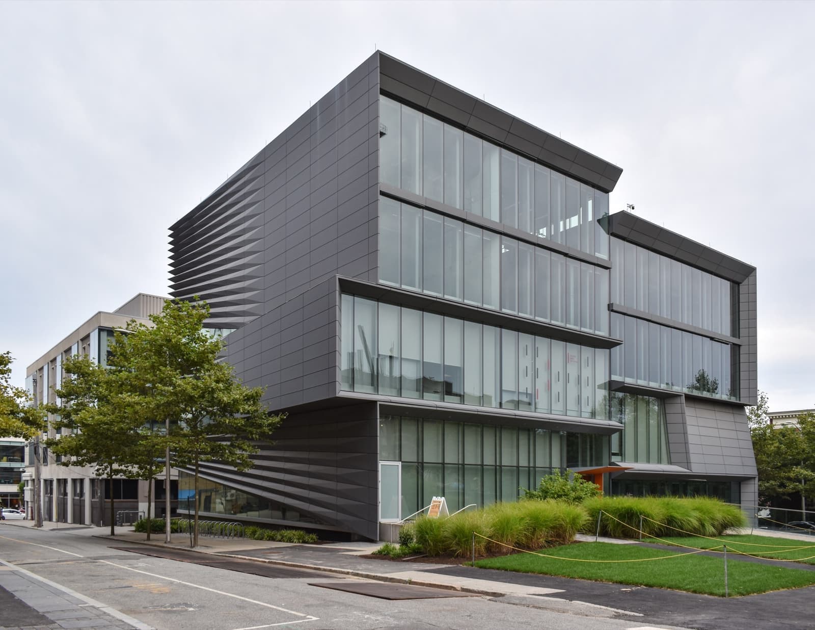 A modern grey building with tall glass bands, split into staggered halves