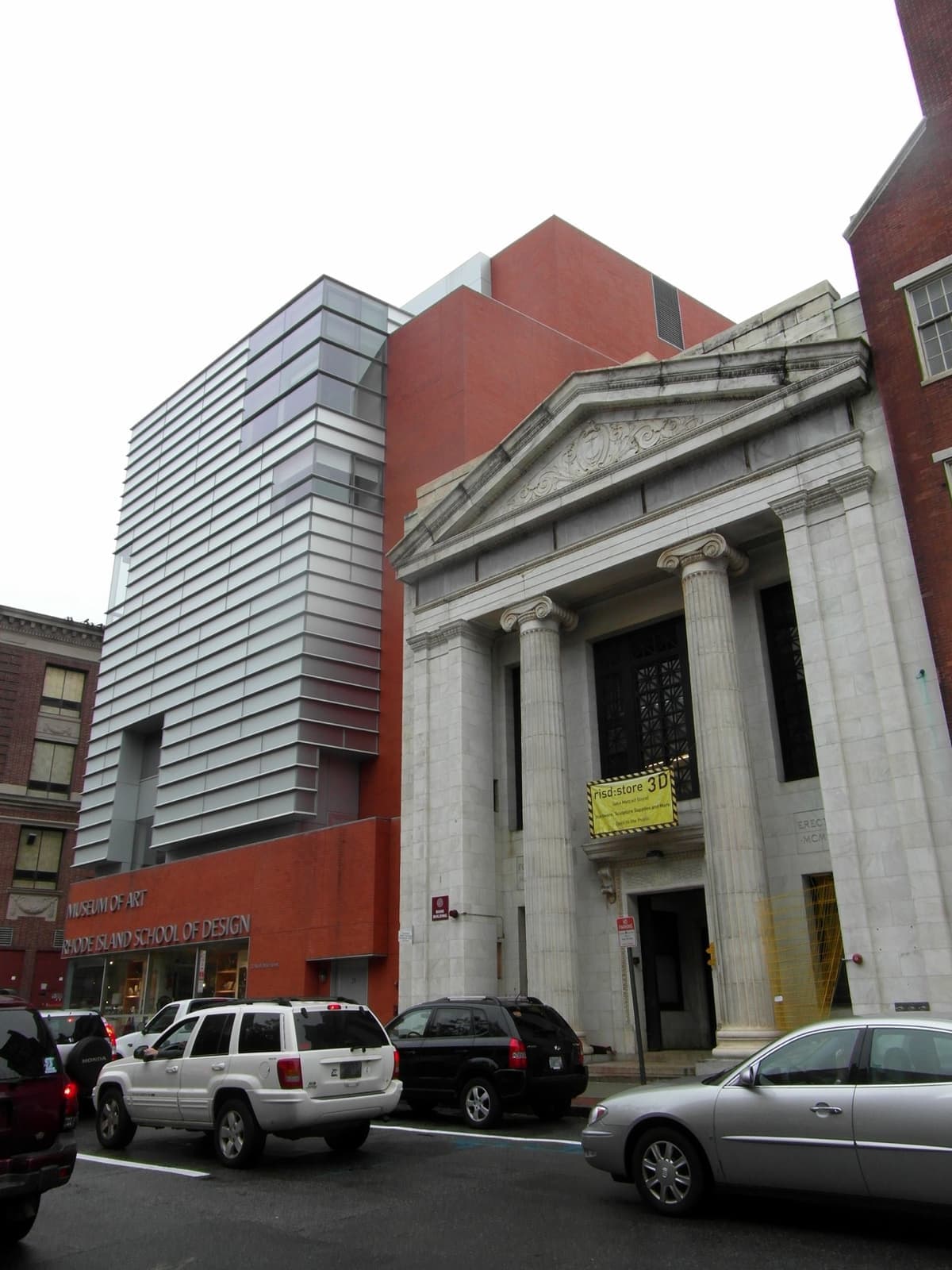 A white columned building and a modern red and glass wing on a Providence street