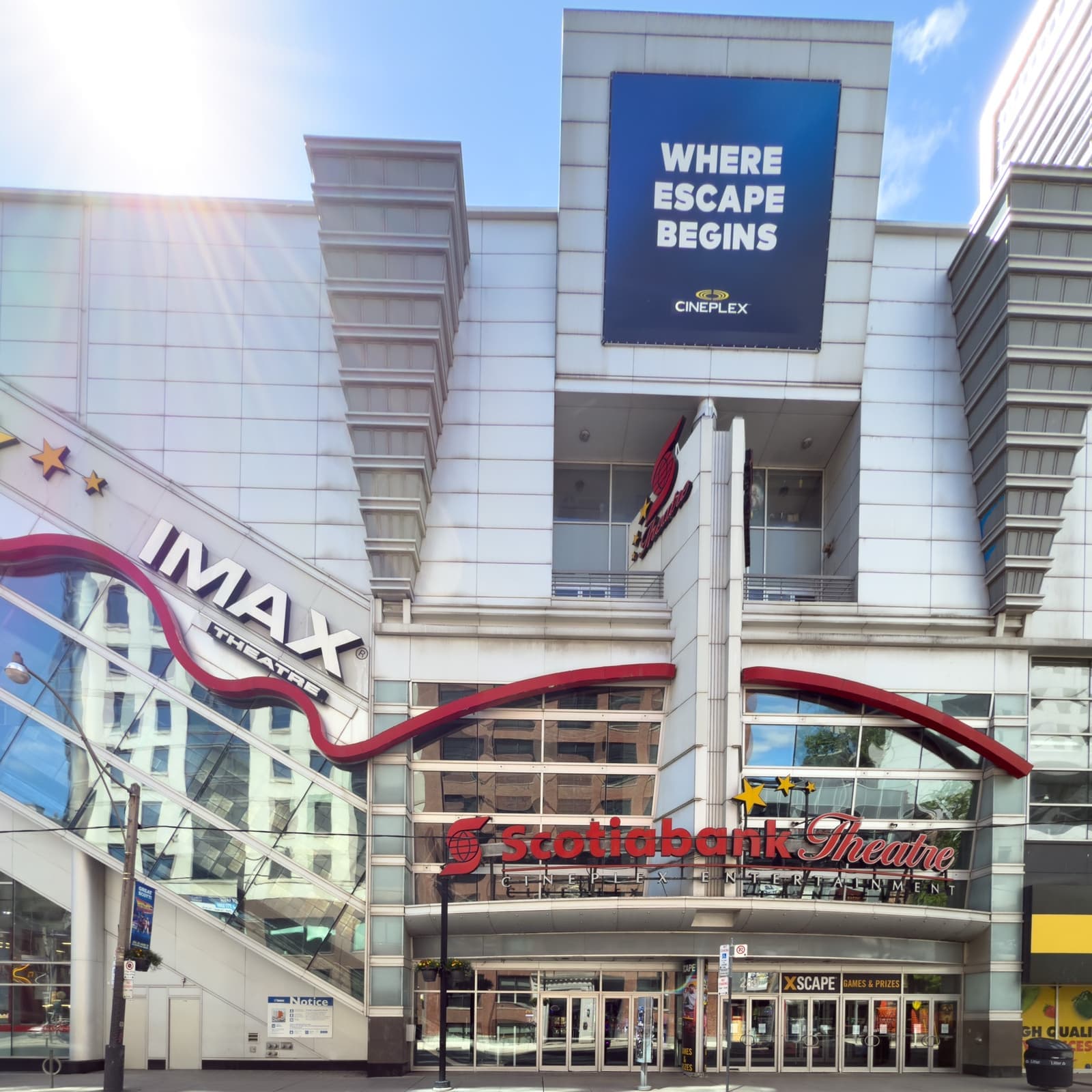 A tall glass and red cinema front with an IMAX sign