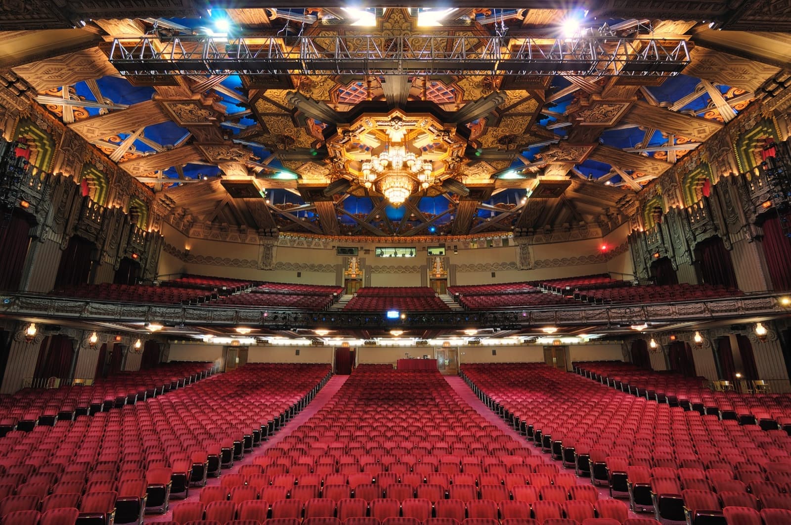 Rows of red seats under a gilded, sculpted ceiling, seen from the stage