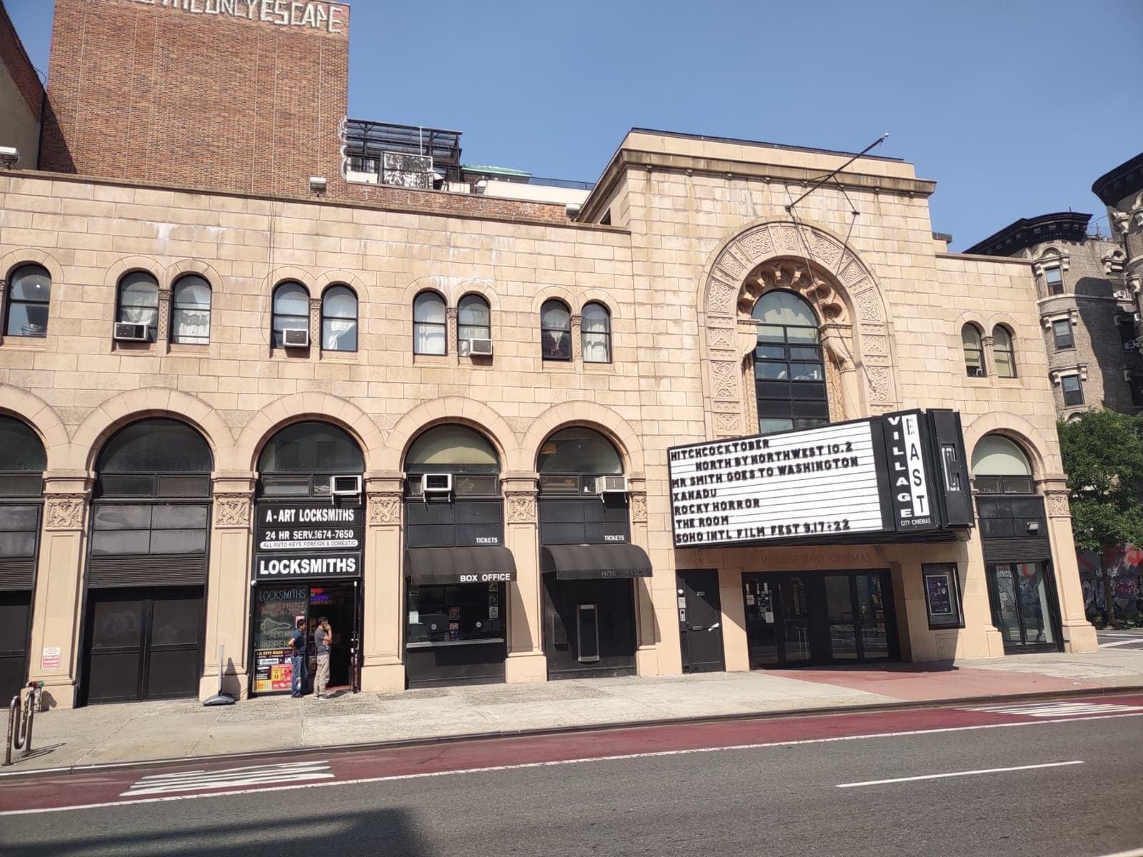 A pale stone theatre front with arched windows and a marquee
