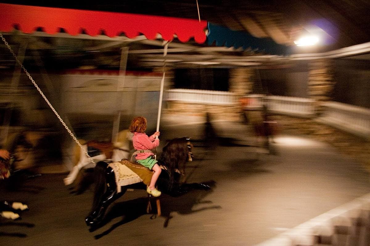 A child on a wooden horse, blurred with speed, on an old carousel