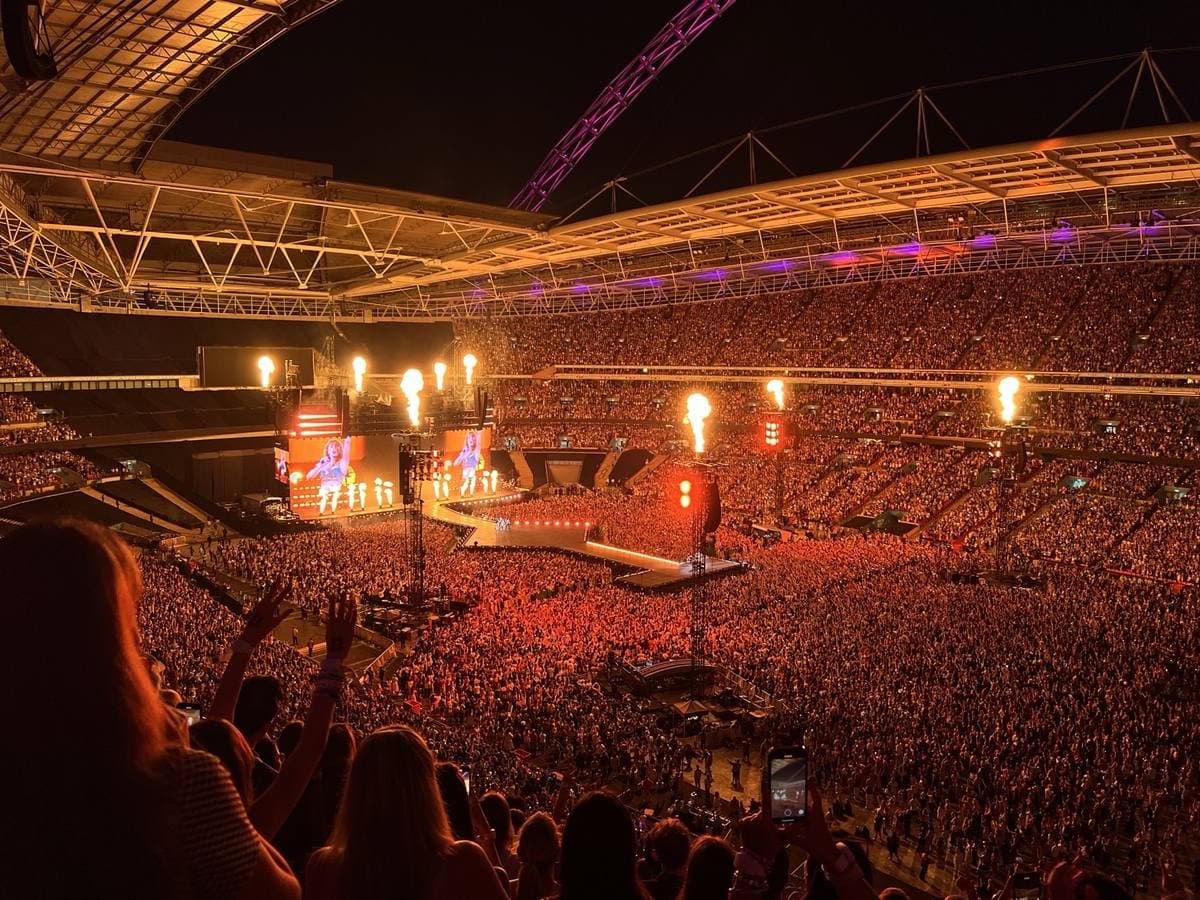 A packed stadium bowl glowing orange under the roof, the stage lit with flames