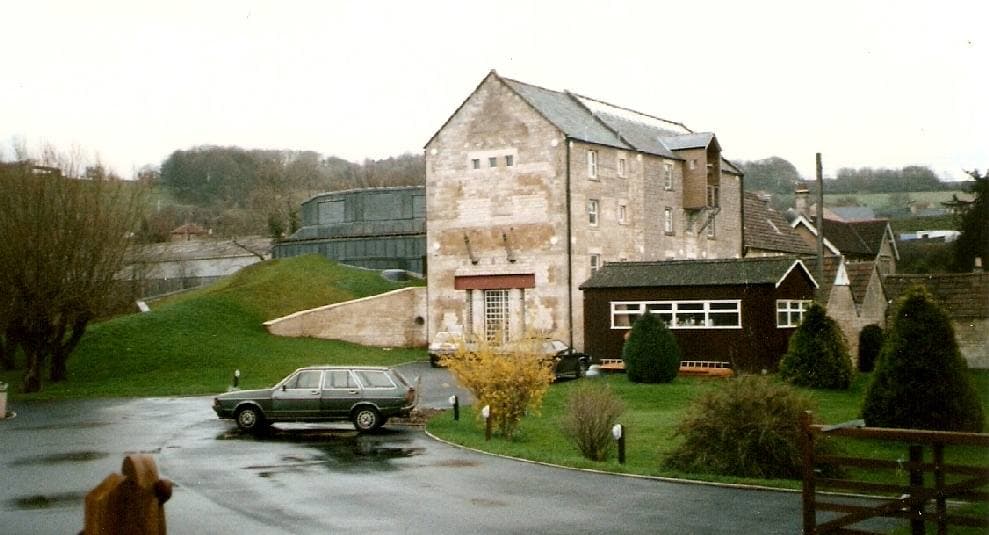 The stone mill buildings of Real World Studios beside the By Brook at Box