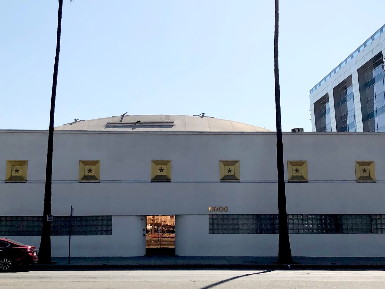 A low white studio building with small square windows on Sunset Boulevard under a blue sky