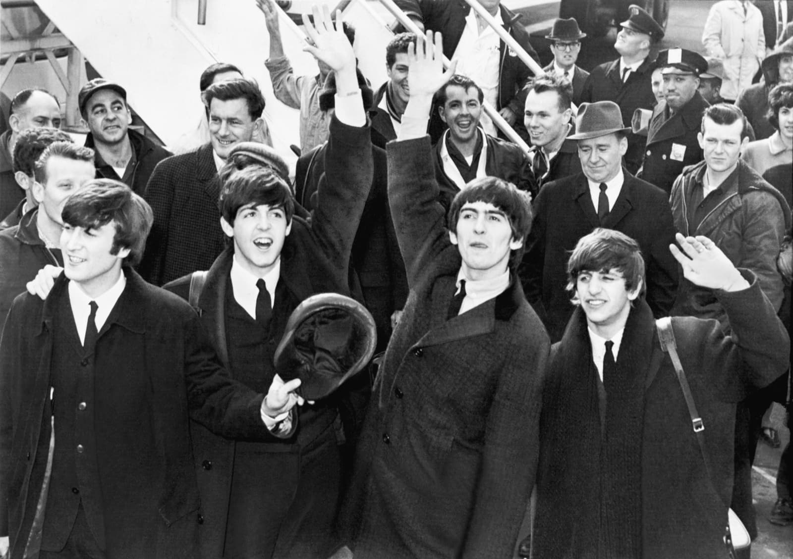 The four Beatles waving on the steps of an aircraft