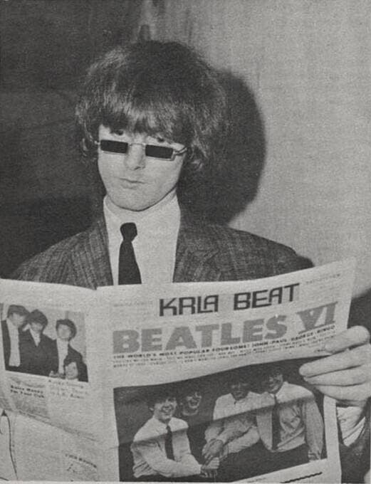 A young man with a long fringe and small rectangular glasses, black and white
