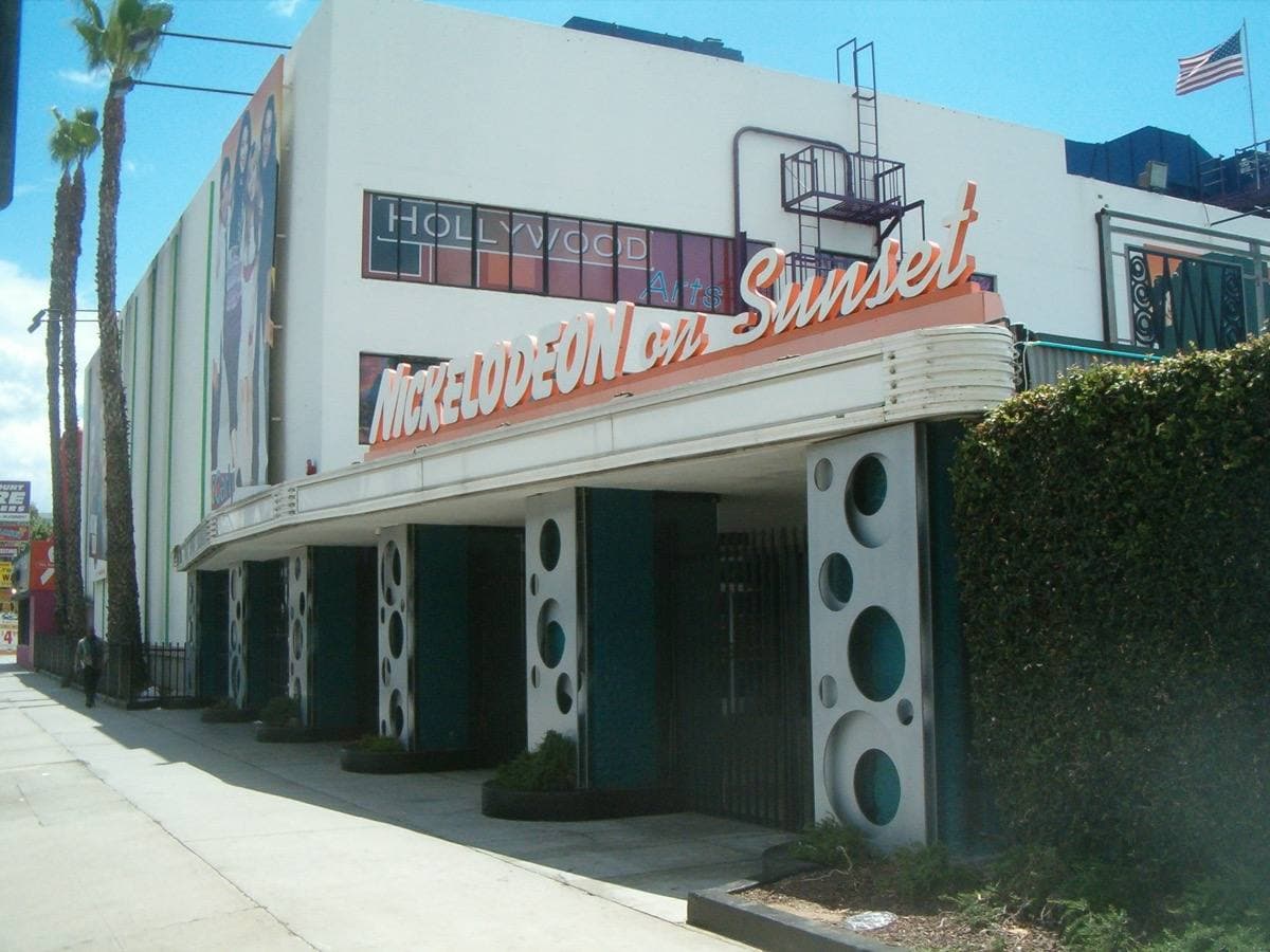 A long white theatre building with a curved orange sign along Sunset Boulevard