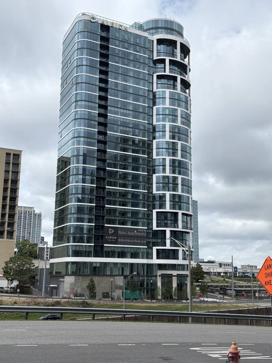 A tall curved glass tower on a Nashville street corner under a grey sky