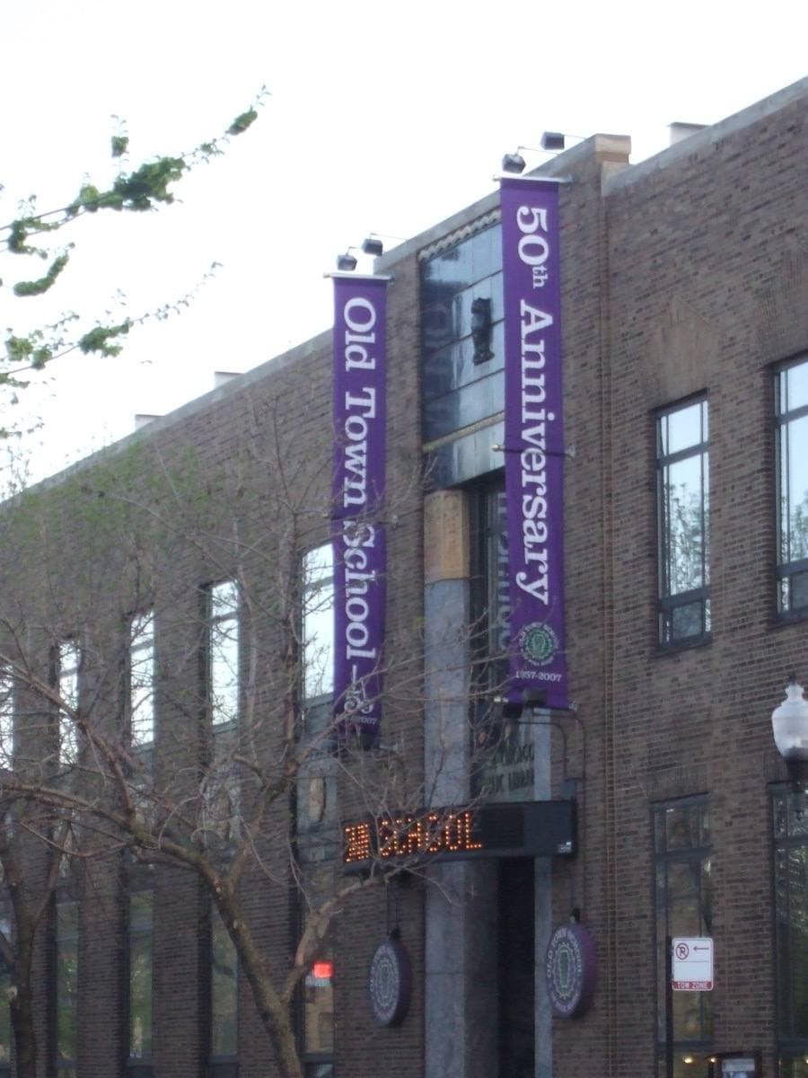A tall brick building with two purple banners for the school’s 50th anniversary
