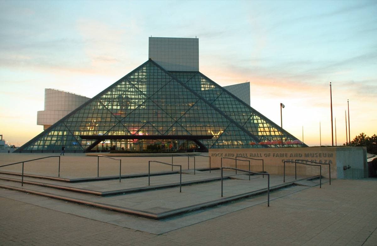 A glass pyramid and white tower beside water at sunset