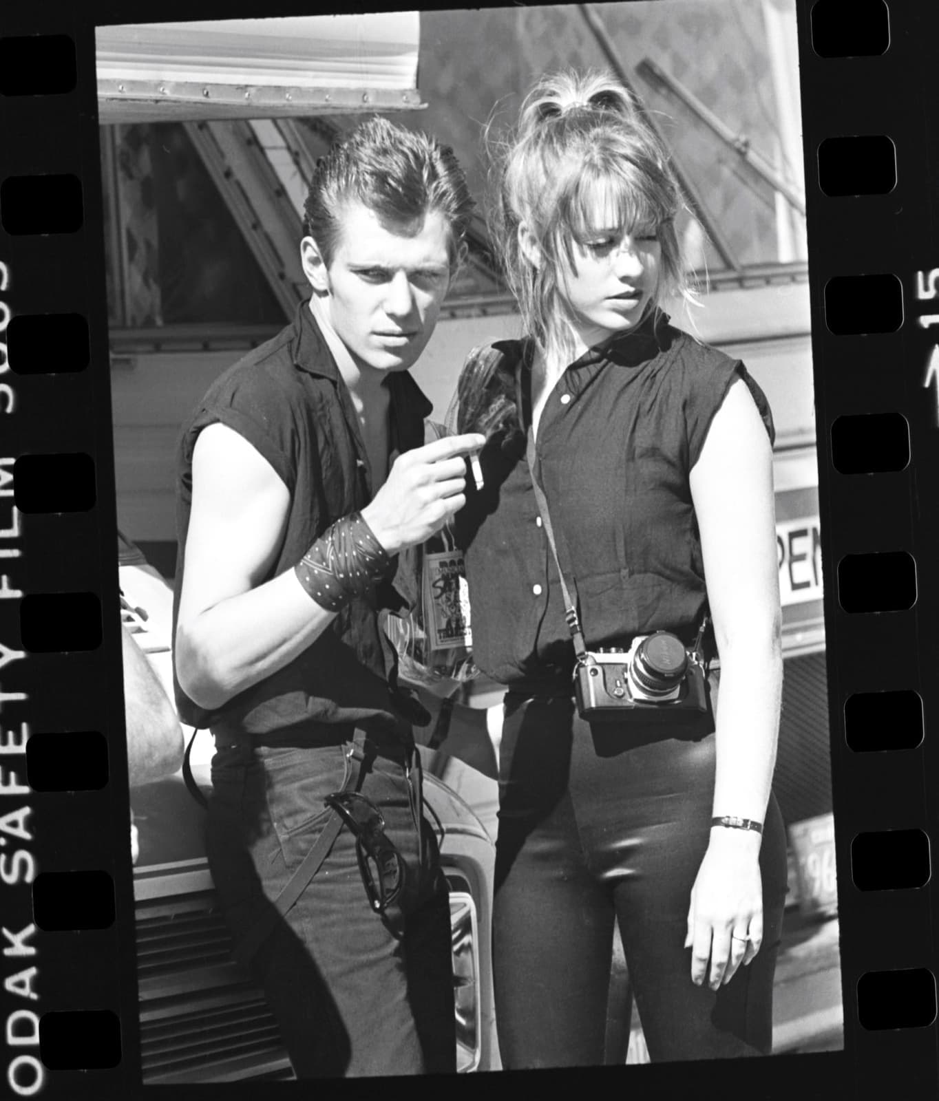 Paul Simonon in a sleeveless shirt beside a young woman with a camera, on a contact-sheet frame