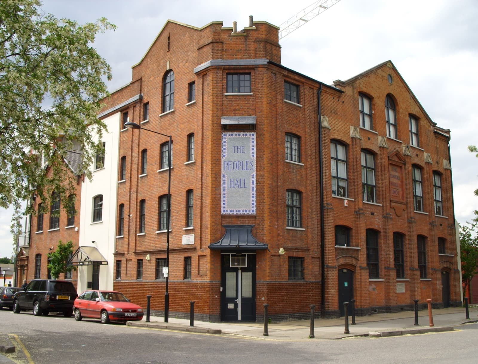 A red-brick hall with tall windows on a street corner