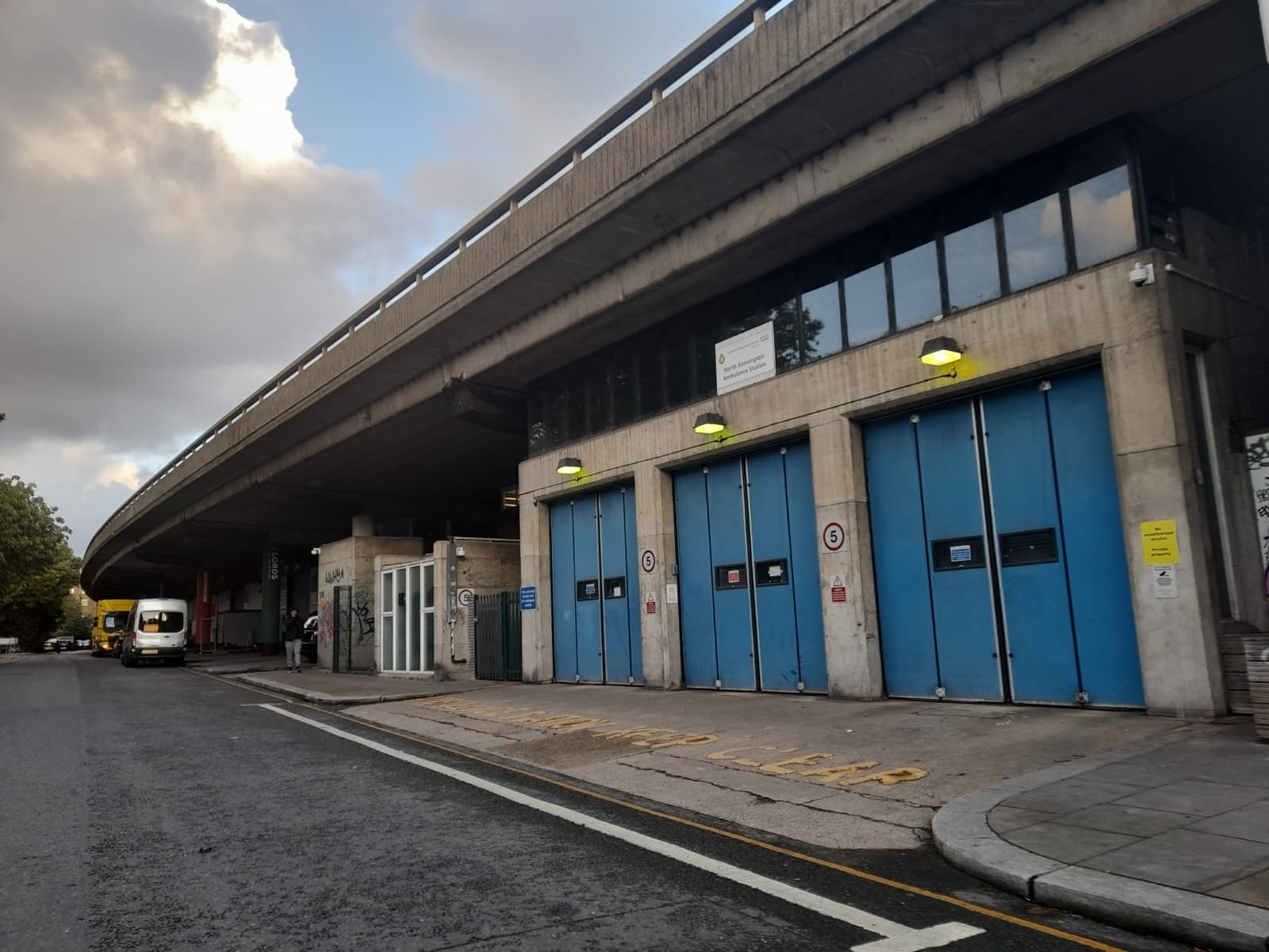 A concrete motorway deck over blue garage doors on a street