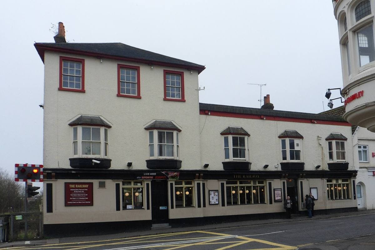 A cream-painted corner pub with red window frames and bay windows on a quiet Crawley street