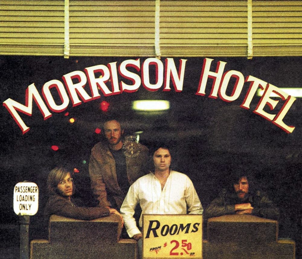 The four Doors seen through a hotel lobby window with a painted sign across the glass