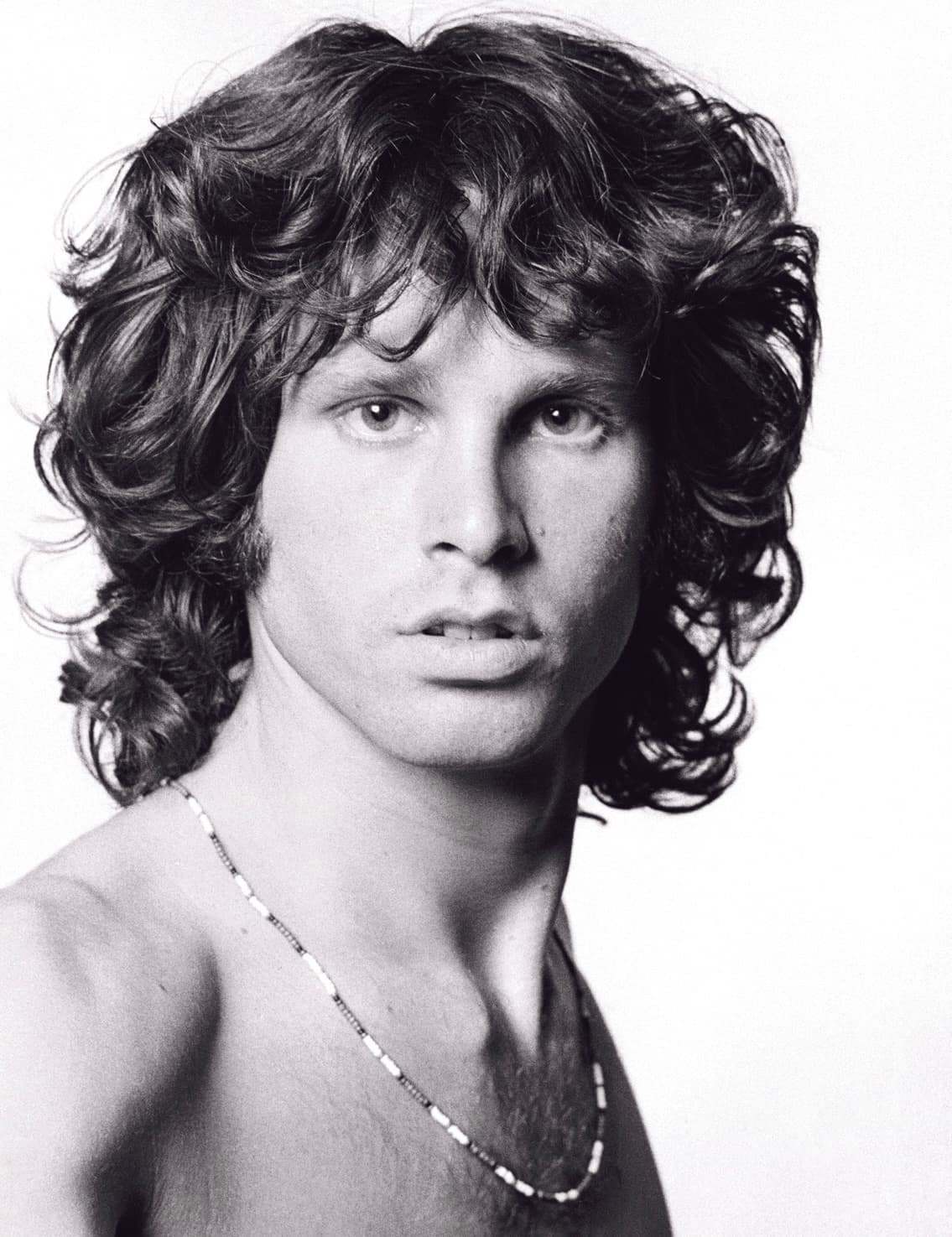 Jim Morrison bare-chested, a string of beads at his neck, looking straight at the camera