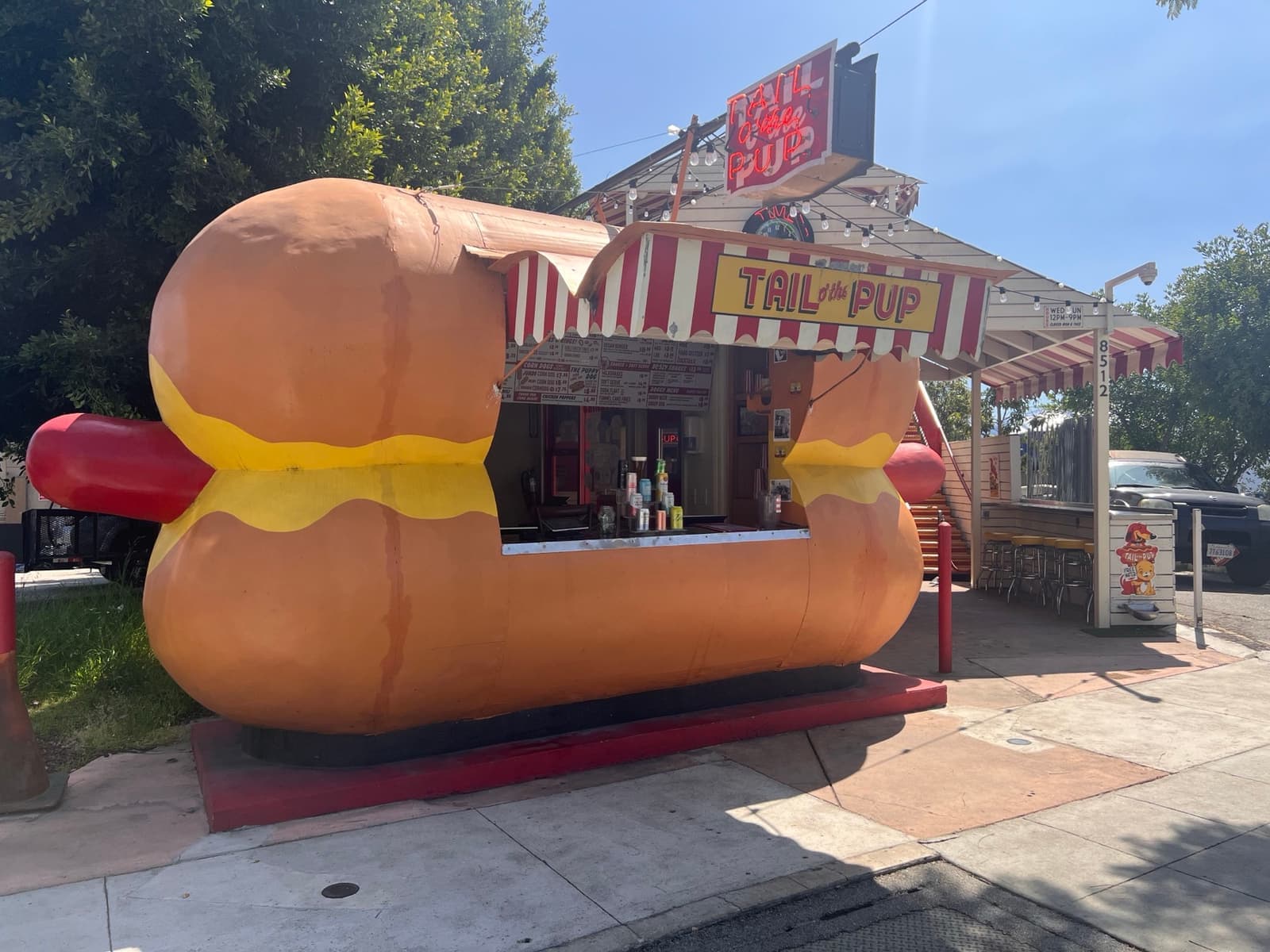 A hot dog stand shaped like a giant hot dog in a bun