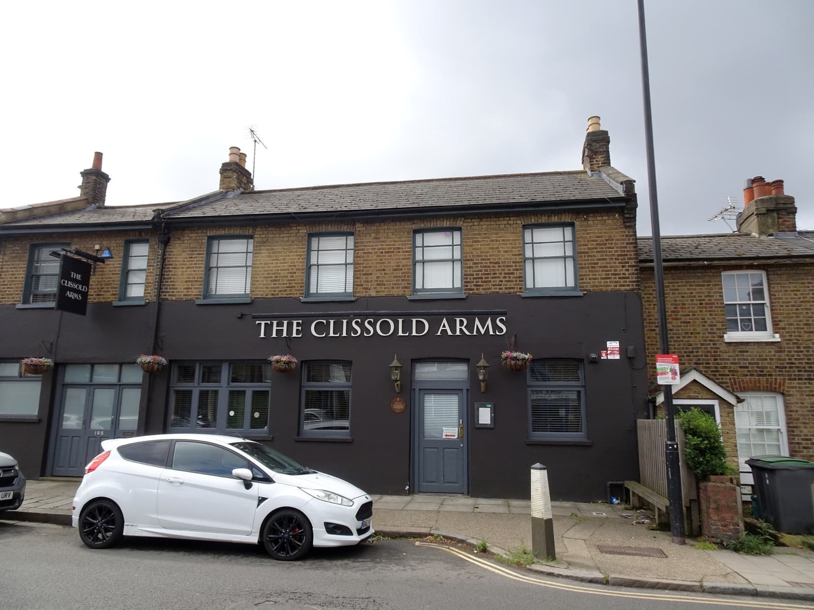 A dark-painted two-storey London pub on a street corner, its name in white letters