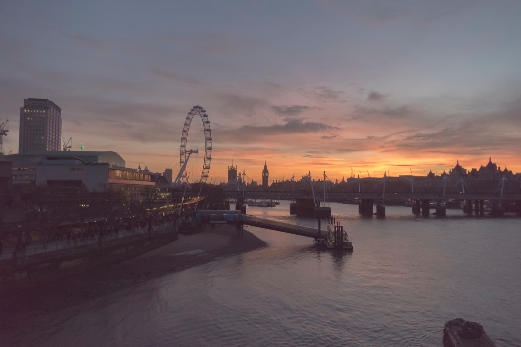 An orange sunset over the Thames with Waterloo Bridge and the London Eye in silhouette