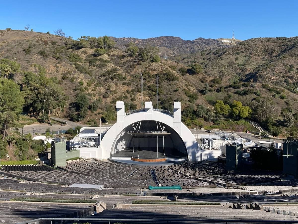 The arched shell of the Hollywood Bowl, rows of seats and the hills behind