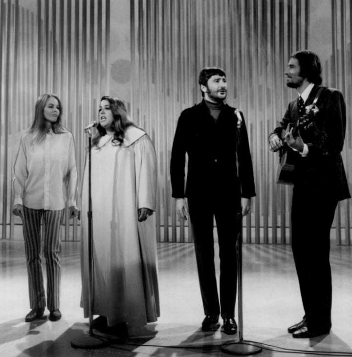 Four singers performing side by side on a television stage