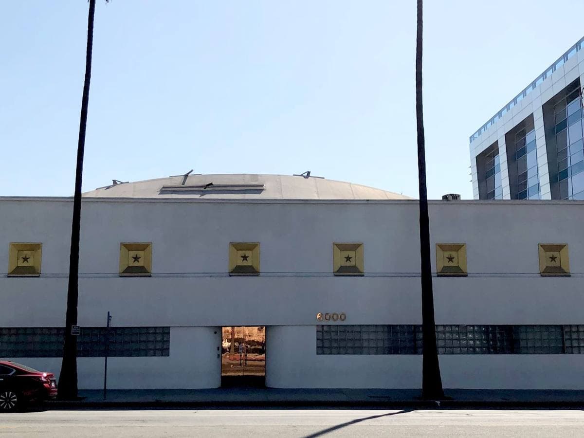 A low white studio building with small square windows on Sunset Boulevard under a blue sky