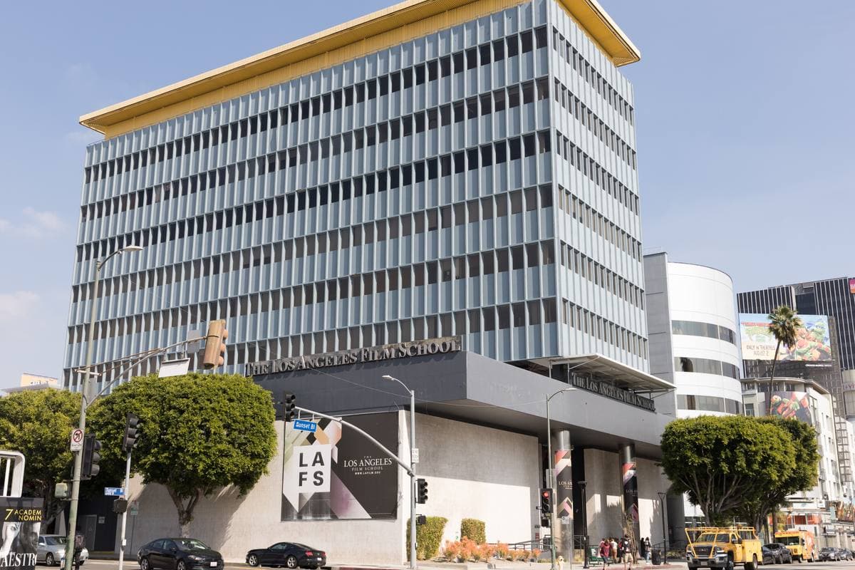 A tall white office building on Sunset Boulevard with a film school sign