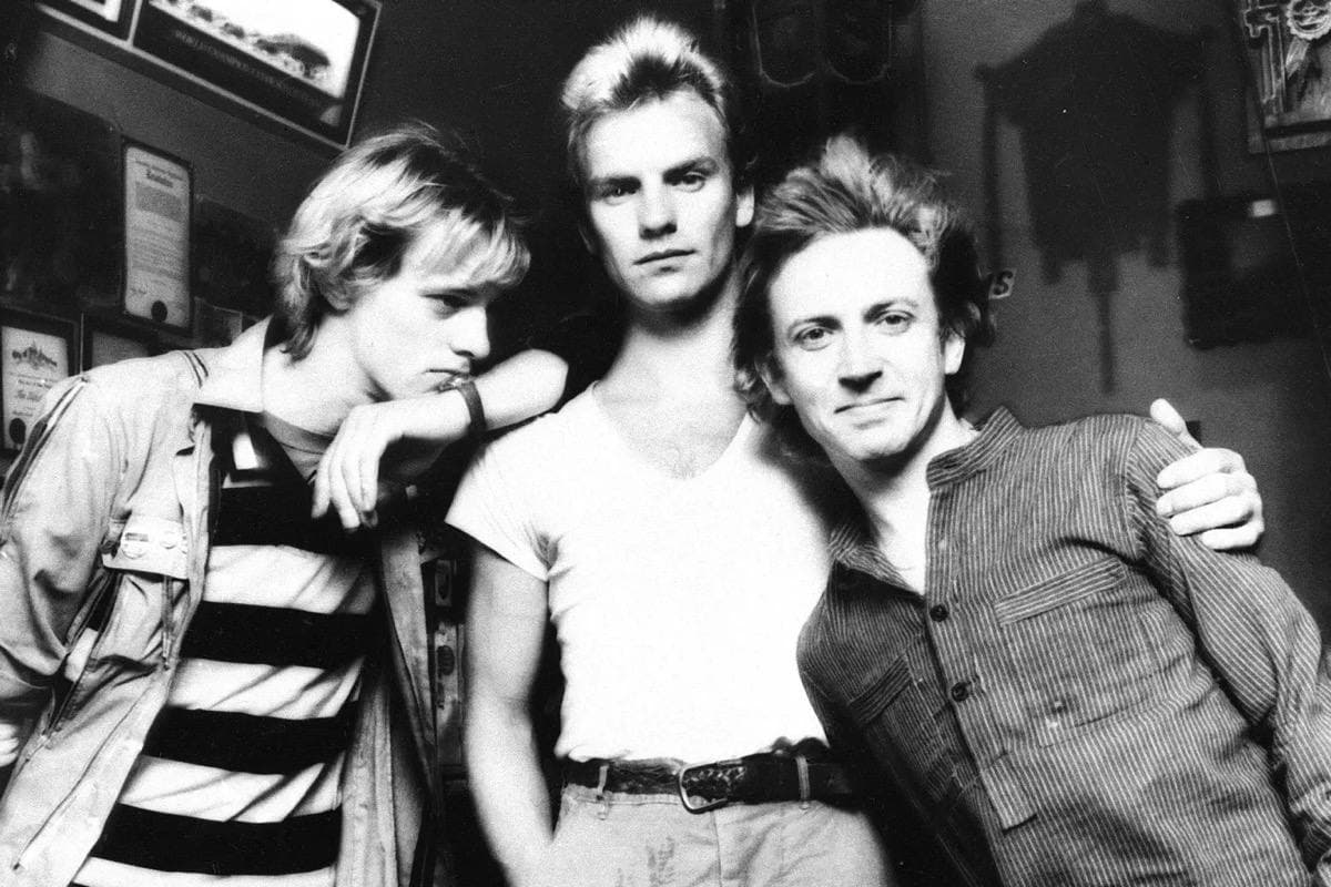 Three young men in black and white, Copeland in a striped top leaning on Sting, Sting in a white T-shirt in the middle, Summers smiling on the right