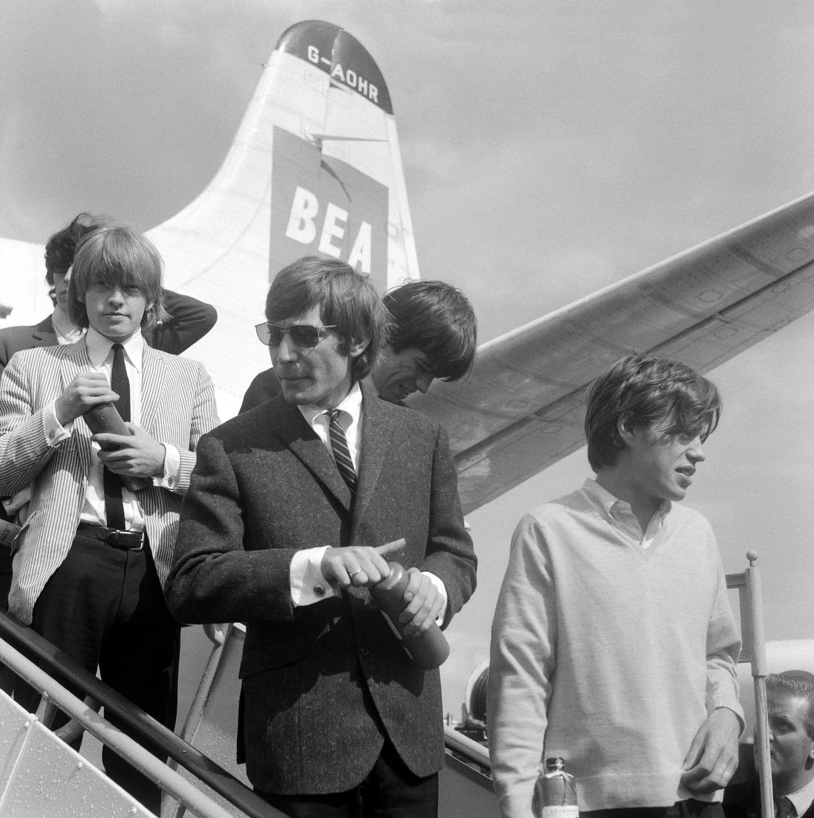 The band in suits and sunglasses coming down the steps of a BEA plane