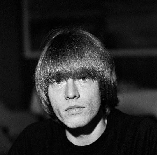Brian Jones, blond fringe, looking straight at the camera in black and white