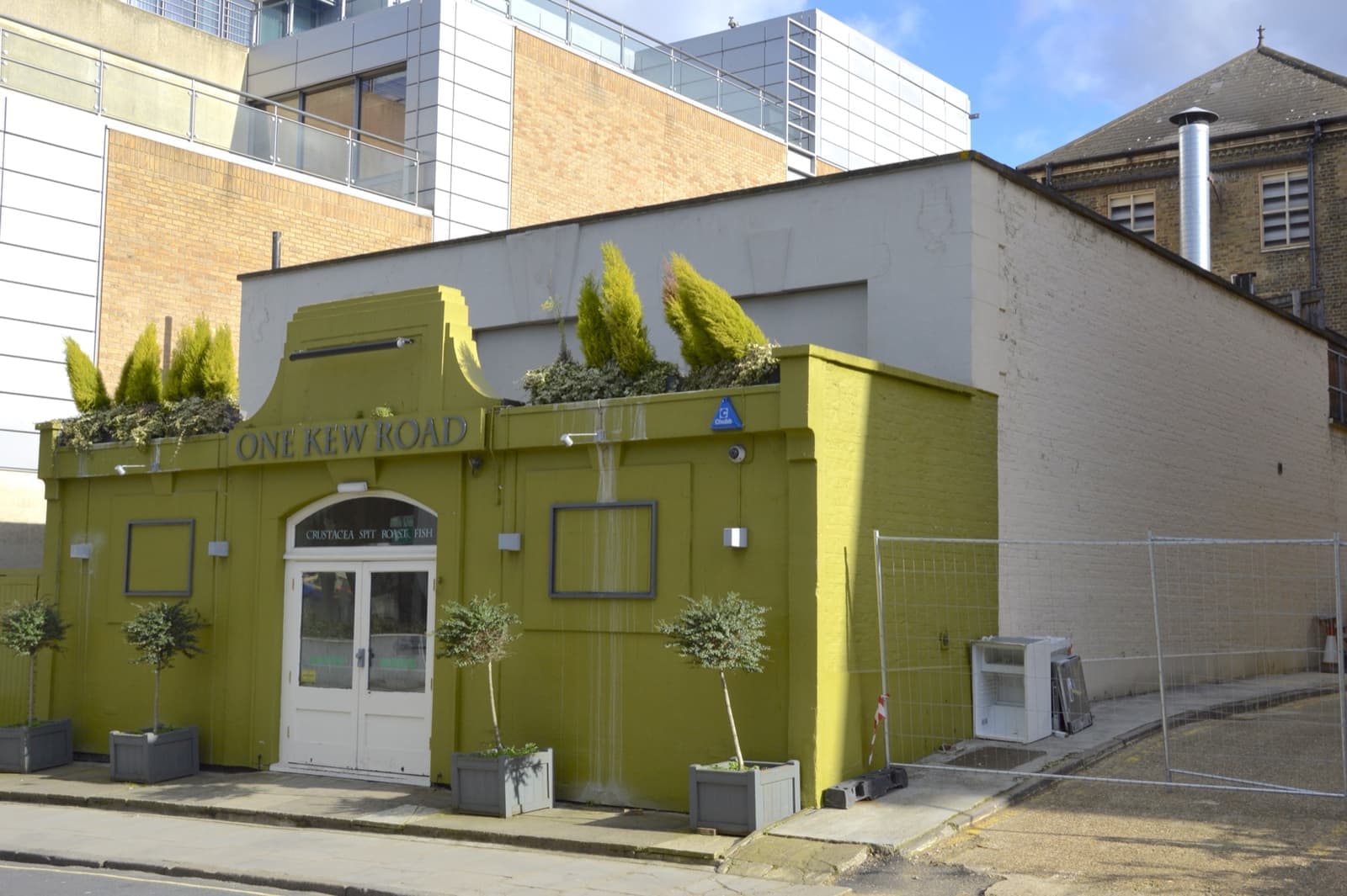 A low painted building with One Kew Road on its front